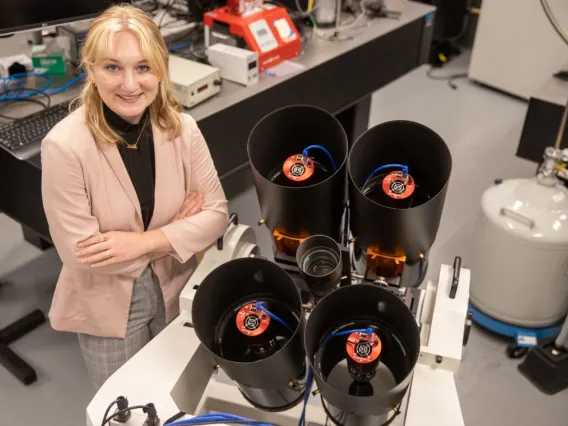 A student stands with the instrument researchers built to measure the brightness and position of SpaceX Starlink satellites.