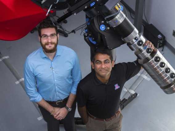 Researchers stand with telescope they used.