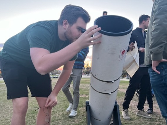 Photo of a student looking though a telescope.