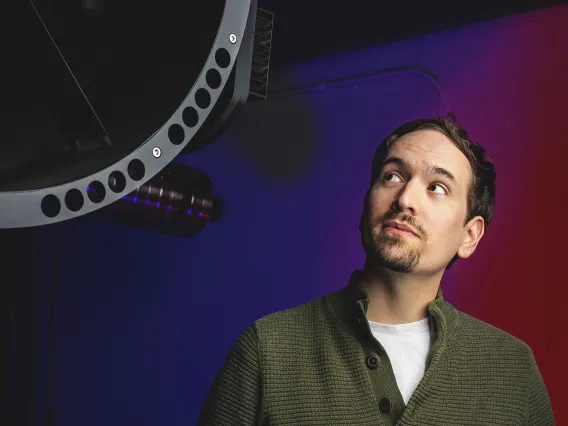 A photo of a student next to a telescope.