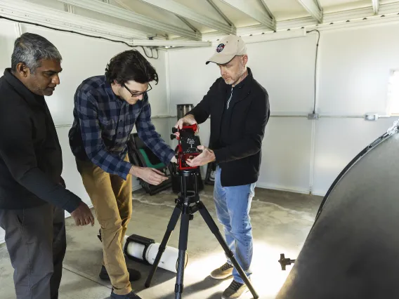 A photo of people setting up a telescope.