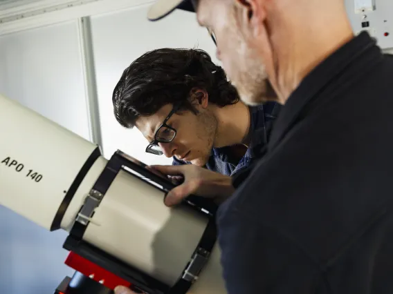 A photo of a student setting up a telescope.