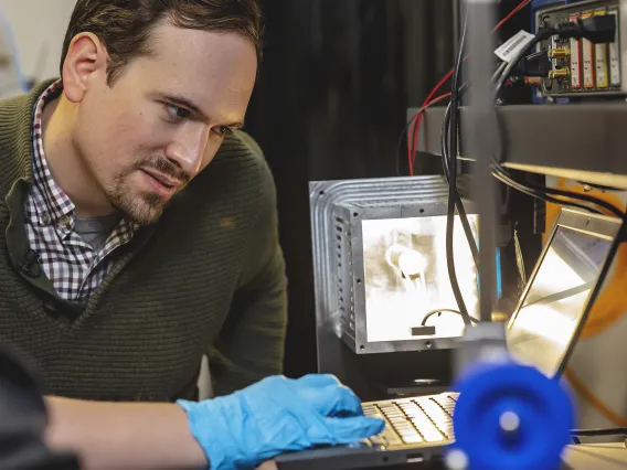 Photo of a graduate student at a laptop in the lab.