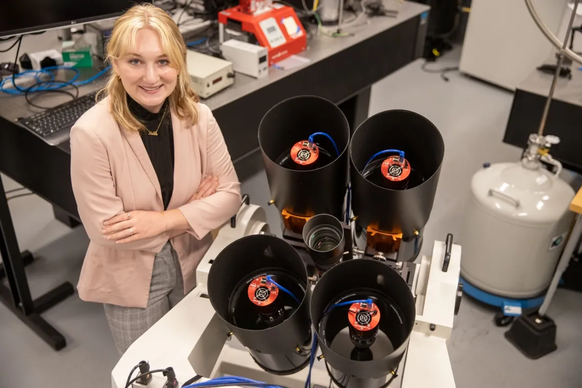 A student stands with the instrument researchers built to measure the brightness and position of SpaceX Starlink satellites.