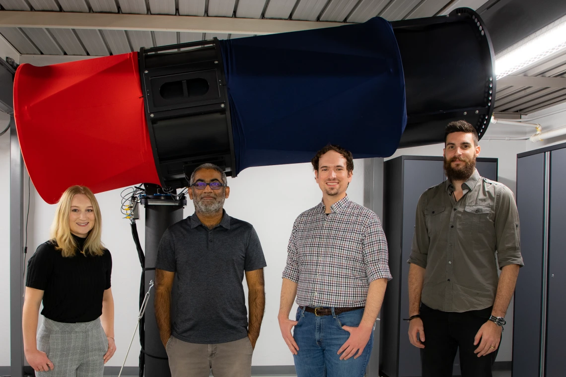 Vishnu Reddy and students standing in front of a telescope used in their research.