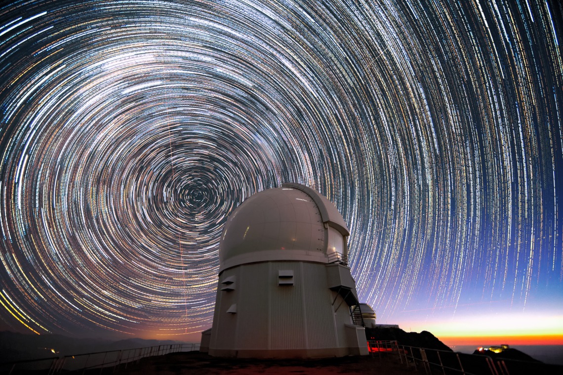 This long-exposure image, taken shortly before sunrise, shows stars appearing to “trail” around the south celestial pole (at the center of the circles) above the Southern Astrophysical Research Telescope (SOAR Telescope)