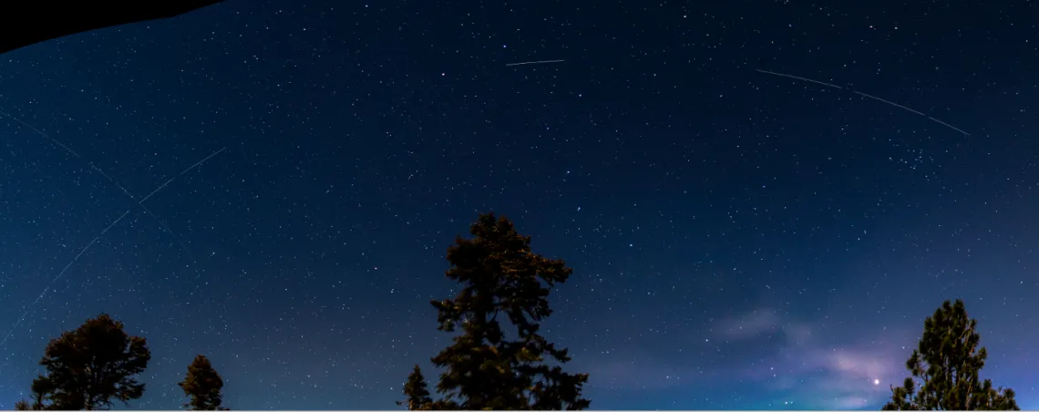 Photo showing bright streaks in an arc across the night sky that are caused by the satellite BlueWalker 3. 