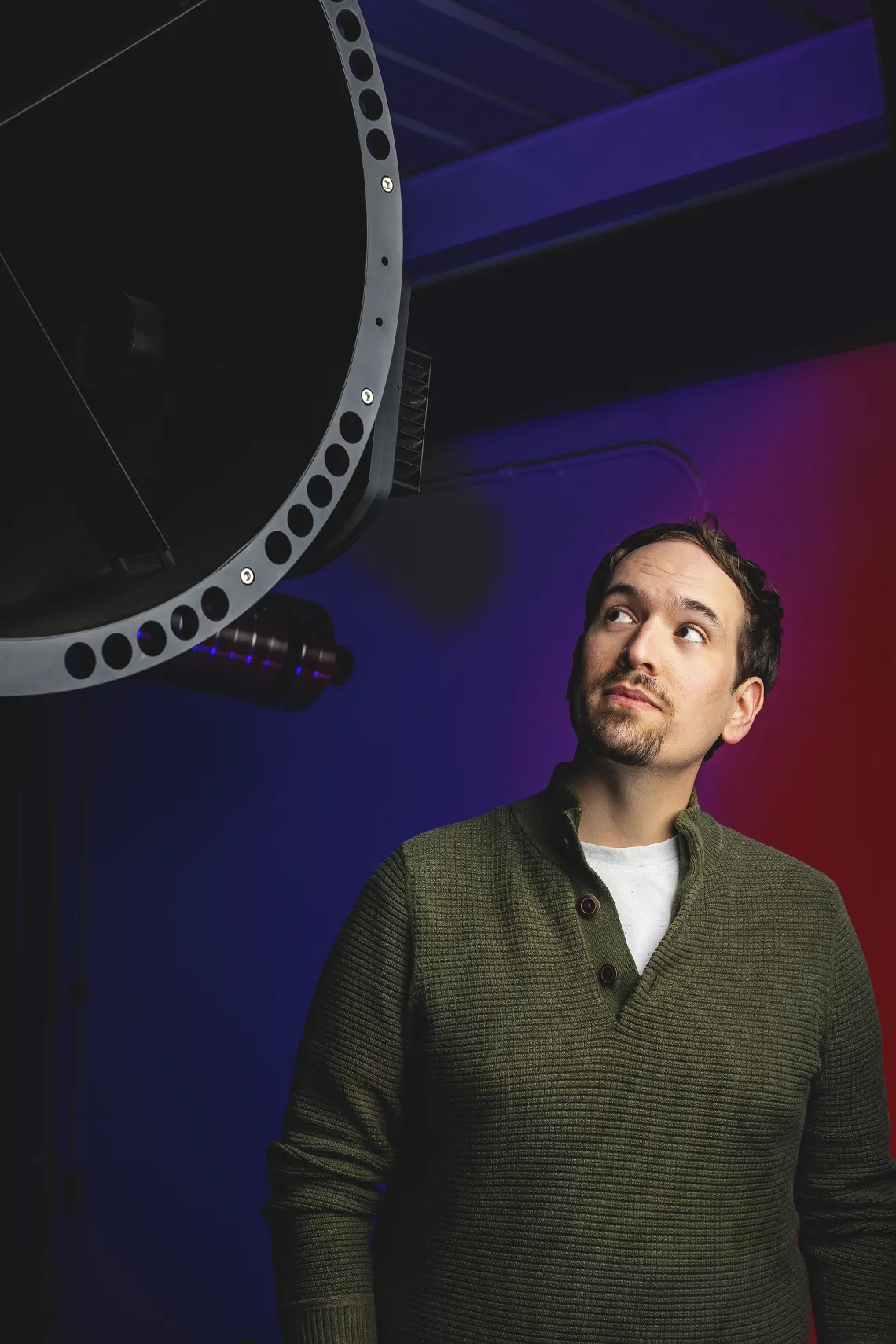 A photo of a student next to a telescope.