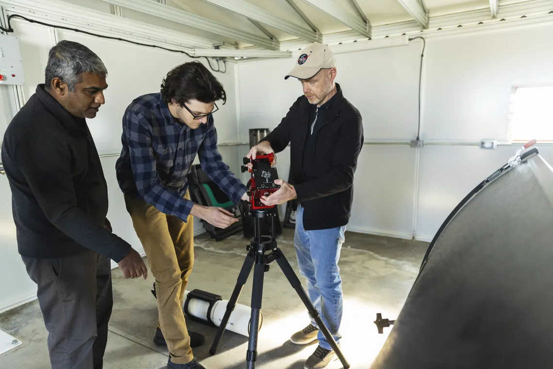 A photo of people setting up a telescope.