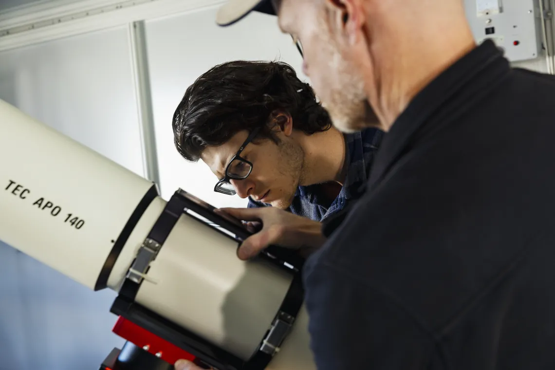 A photo of a student setting up a telescope.