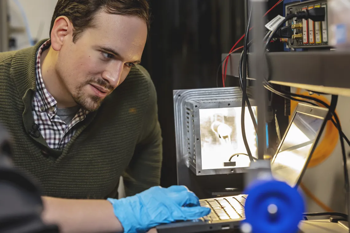 Photo of a graduate student at a laptop in the lab.