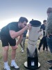Photo of a student looking though a telescope.
